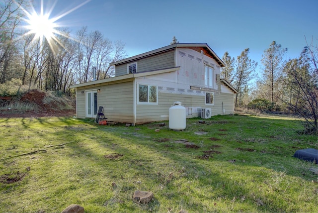 back of property featuring a lawn and ac unit