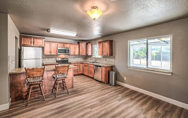 kitchen featuring wood-type flooring, sink, a breakfast bar area, backsplash, and stainless steel appliances