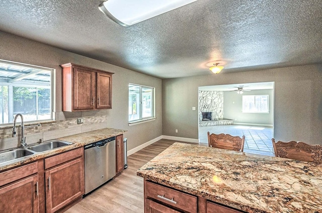 kitchen with tasteful backsplash, dishwasher, sink, light hardwood / wood-style floors, and a textured ceiling