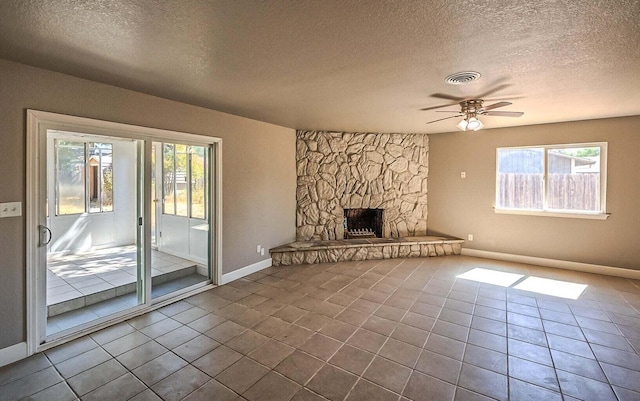 unfurnished living room with a textured ceiling, a fireplace, tile patterned floors, and ceiling fan