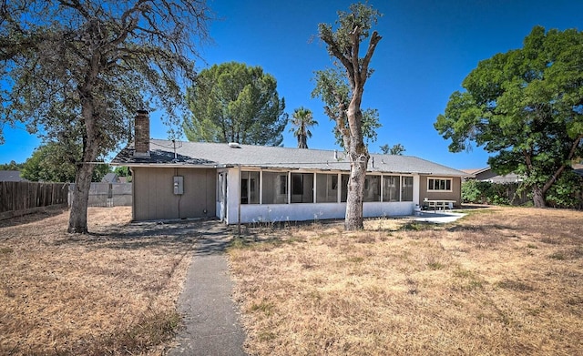 back of property featuring a patio, a sunroom, and a lawn