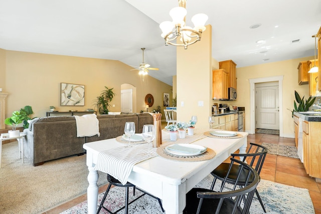 tiled dining room with ceiling fan with notable chandelier and vaulted ceiling