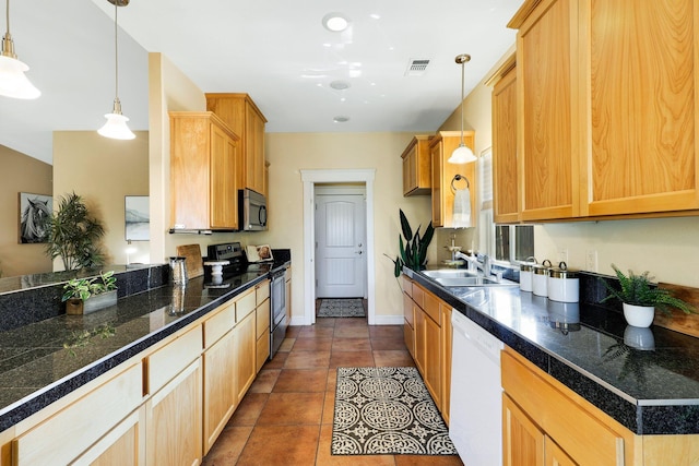 kitchen with appliances with stainless steel finishes, pendant lighting, light brown cabinetry, sink, and dark tile patterned flooring