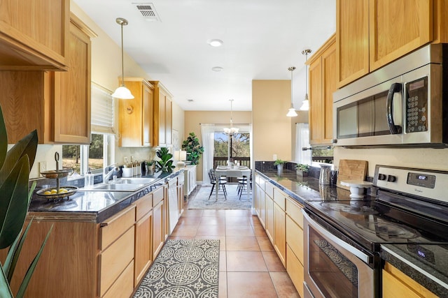 kitchen featuring pendant lighting, light tile patterned floors, plenty of natural light, and stainless steel appliances