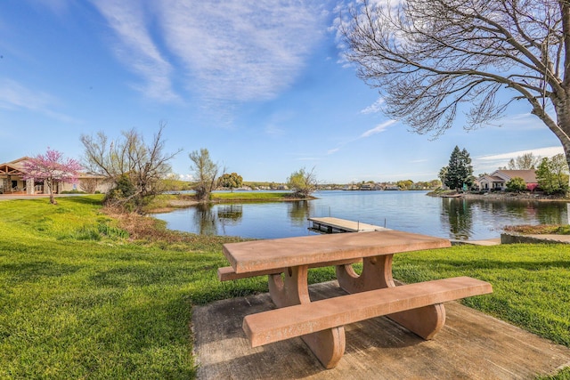 view of dock with a yard and a water view