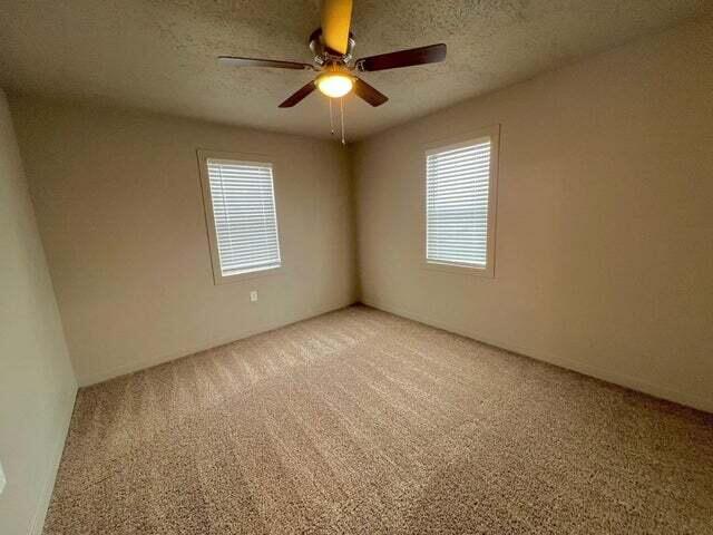 unfurnished room with ceiling fan, carpet flooring, and a textured ceiling