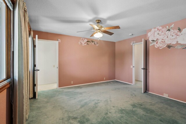 carpeted empty room featuring a ceiling fan and baseboards
