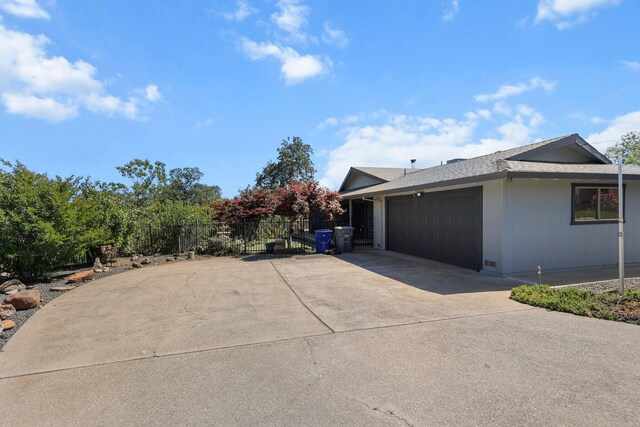view of home's exterior featuring an attached garage, fence, and concrete driveway