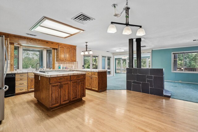 kitchen with visible vents, tile countertops, a center island, brown cabinetry, and open floor plan