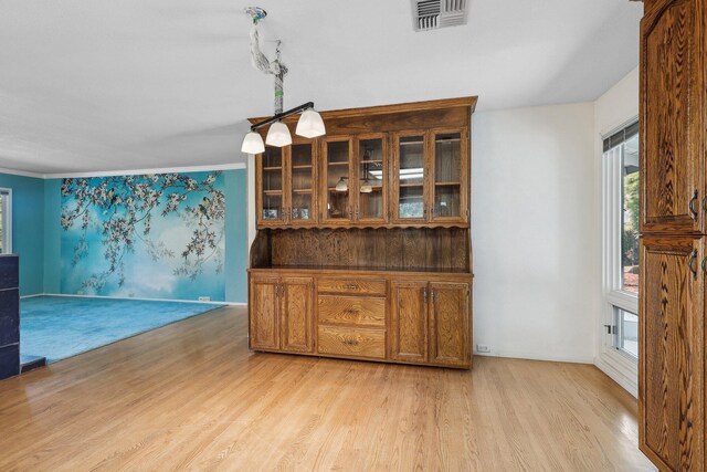 dining area featuring light wood finished floors, visible vents, and crown molding
