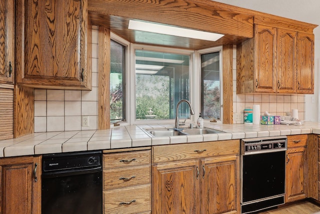 kitchen featuring tile counters, brown cabinets, decorative backsplash, and a sink