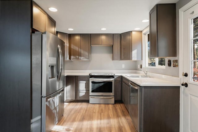 kitchen featuring appliances with stainless steel finishes, sink, and light wood-type flooring