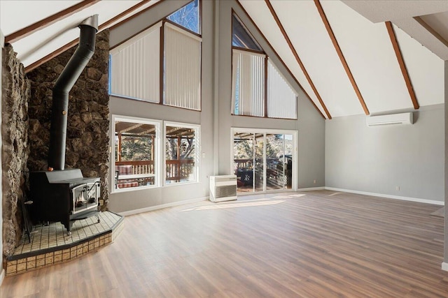 unfurnished living room with a wall mounted AC, high vaulted ceiling, a wood stove, beamed ceiling, and hardwood / wood-style floors