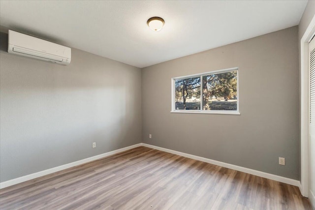 unfurnished room with hardwood / wood-style floors and an AC wall unit