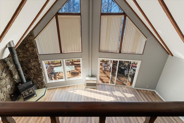 unfurnished living room with hardwood / wood-style flooring, a towering ceiling, and a wood stove