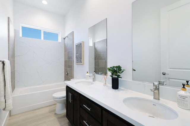 full bathroom with hardwood / wood-style flooring, tiled shower / bath, vanity, and toilet