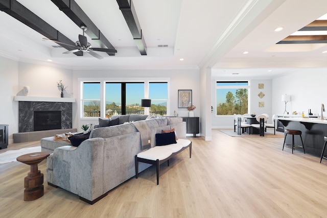 living room with light hardwood / wood-style flooring, beam ceiling, and plenty of natural light