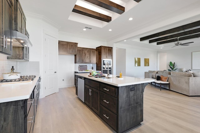 kitchen with sink, backsplash, stainless steel appliances, an island with sink, and light wood-type flooring