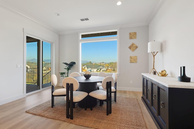 dining space with ornamental molding and light hardwood / wood-style floors