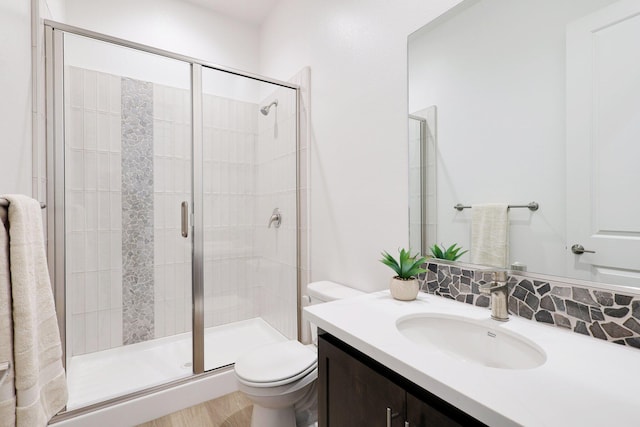 bathroom featuring vanity, a shower with shower door, and toilet