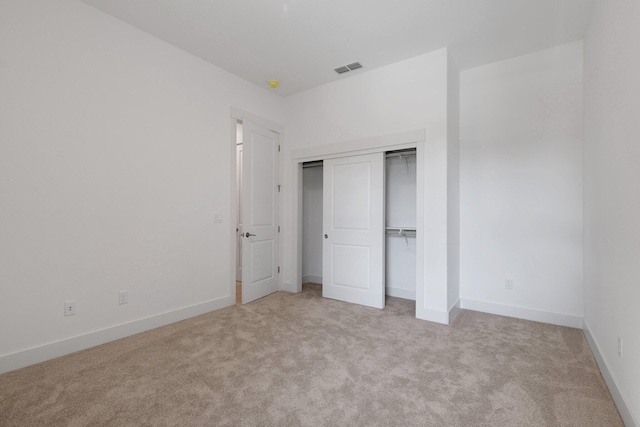 unfurnished bedroom featuring light carpet and a closet