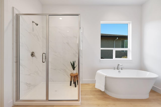 bathroom featuring wood-type flooring and shower with separate bathtub