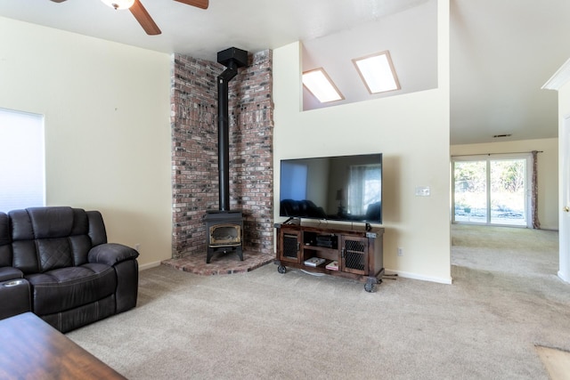 living room featuring high vaulted ceiling, light colored carpet, ceiling fan, and a wood stove