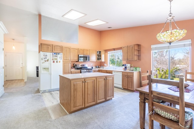 kitchen featuring appliances with stainless steel finishes, decorative light fixtures, a center island, and high vaulted ceiling