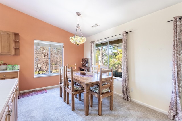 carpeted dining room with vaulted ceiling