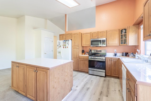 kitchen featuring sink, stainless steel appliances, a center island, light brown cabinets, and light wood-type flooring