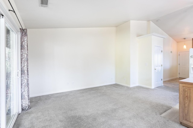 spare room featuring lofted ceiling and light colored carpet