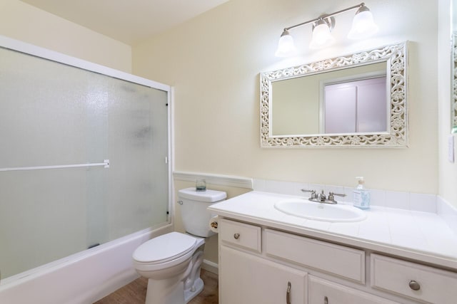 full bathroom featuring enclosed tub / shower combo, vanity, and toilet