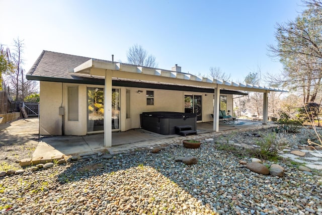 rear view of house featuring a hot tub and a patio