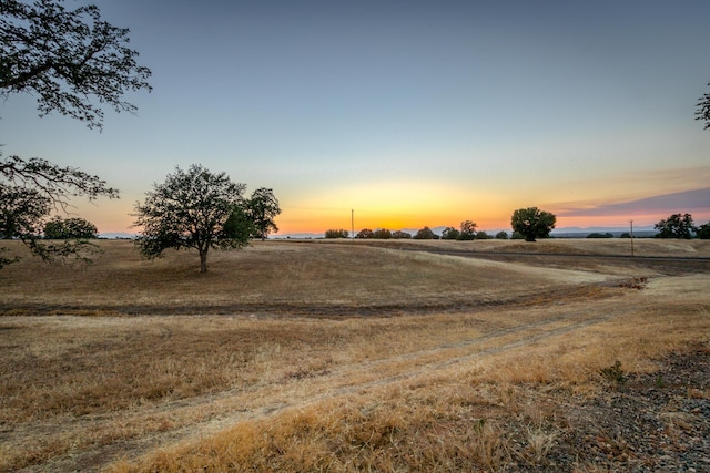 yard at dusk featuring a rural view