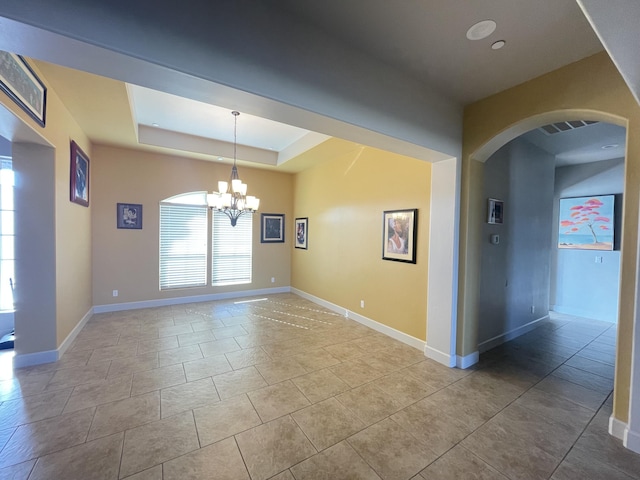 spare room with an inviting chandelier, light tile patterned floors, and a tray ceiling