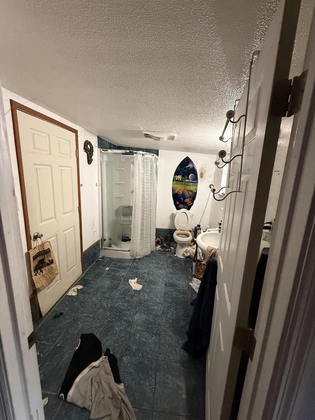 bathroom featuring curtained shower, toilet, and a textured ceiling