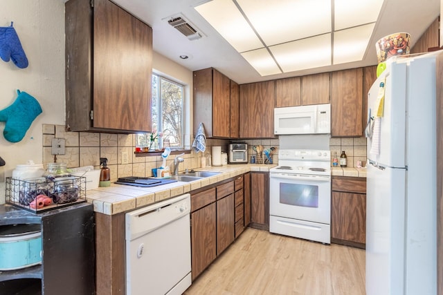 kitchen featuring sink, tasteful backsplash, tile countertops, white appliances, and light hardwood / wood-style floors