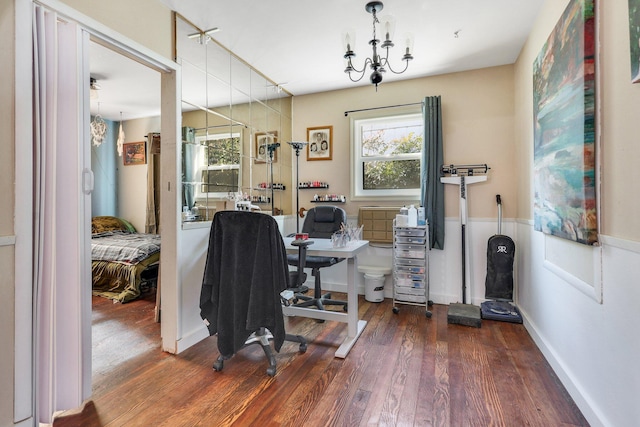 home office with dark wood-type flooring, a healthy amount of sunlight, and an inviting chandelier