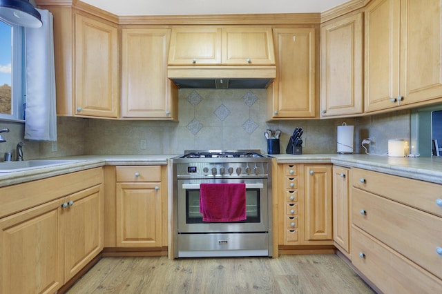 kitchen featuring light brown cabinetry, sink, decorative backsplash, light hardwood / wood-style floors, and stainless steel gas range