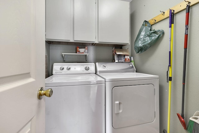 clothes washing area with cabinets and washing machine and clothes dryer