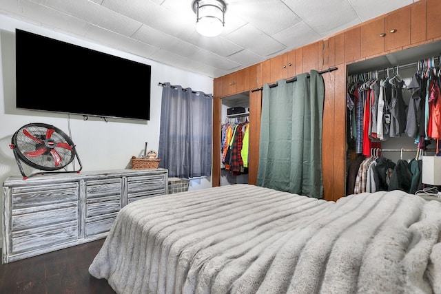 bedroom with wooden walls and dark hardwood / wood-style flooring