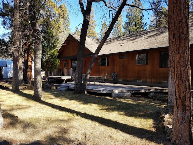 rear view of property featuring a yard, crawl space, and a wooden deck