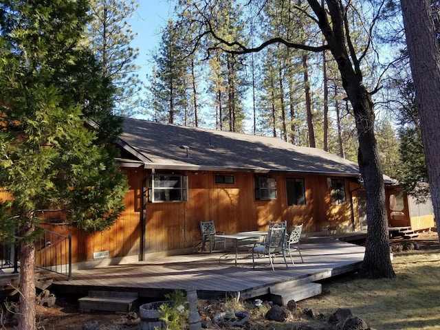 rear view of house featuring a shingled roof and a wooden deck