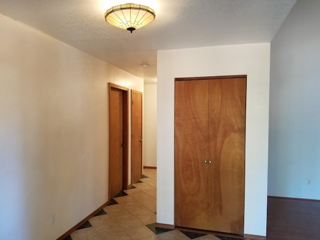 hallway with baseboards and a textured ceiling