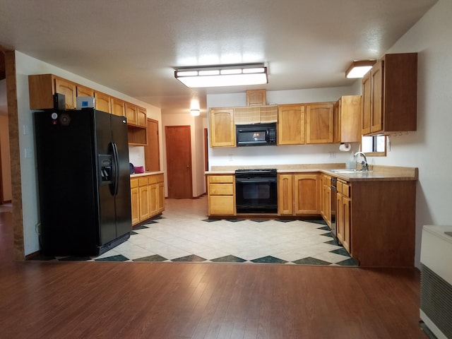 kitchen with black appliances, light wood-style floors, light countertops, and a sink