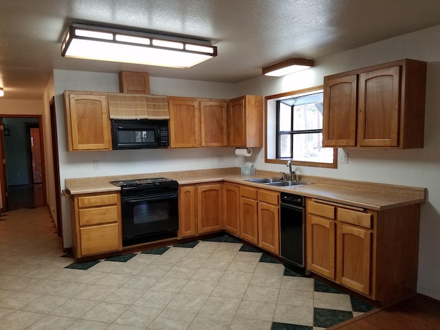 kitchen with brown cabinets, light countertops, a sink, a textured ceiling, and black appliances