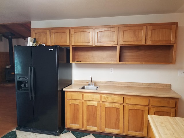 kitchen with wooden counters, black refrigerator with ice dispenser, a sink, and open shelves