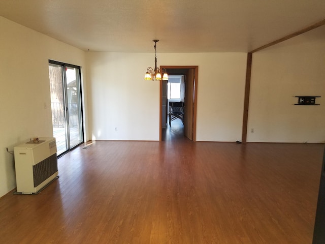 unfurnished room featuring heating unit, plenty of natural light, and dark wood-style flooring