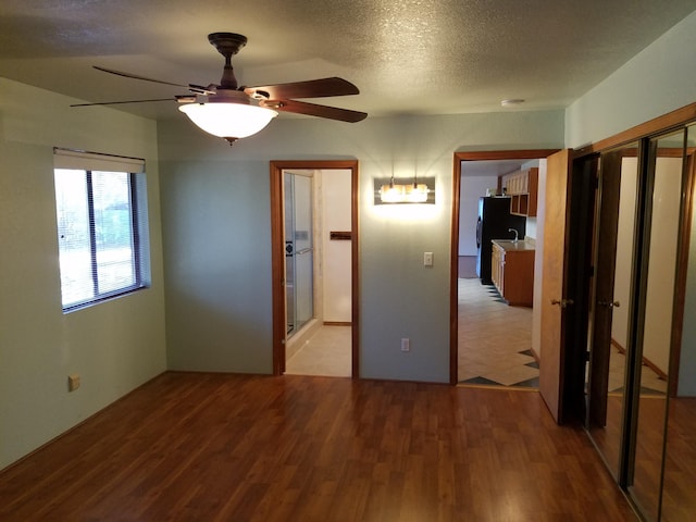 unfurnished bedroom featuring light wood-style floors, ceiling fan, a textured ceiling, and freestanding refrigerator