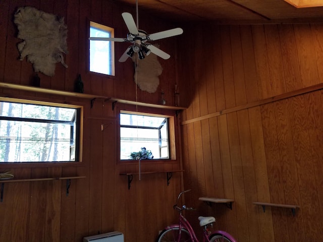 interior space with ceiling fan and wooden walls